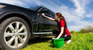 Jeune femme nettoyant sa voiture à l'extérieur