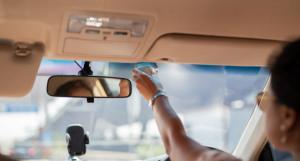 Une personne accrochant un badge de télépéage dans sa voiture