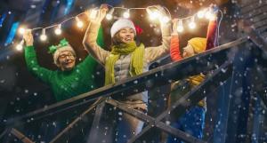 Famille qui accroche des guirlandes lumineuses de Noël sur sa maison