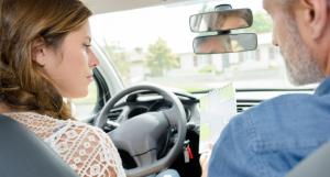 Une jeune fille au volant d'une voiture à côté d'un moniteur d'auto-école