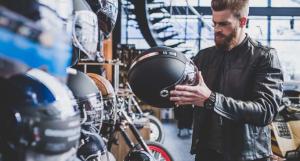 Un homme barbu en train de choisir un casque de scooter dans un magasin spécialisé