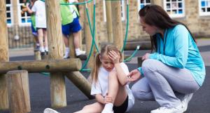 Une enfant blessée au genou et une adulte à ses côtés pour la consoler