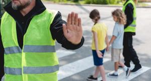 Deux enfants traversant sur le passage piéton encadrés par des agents de circulation