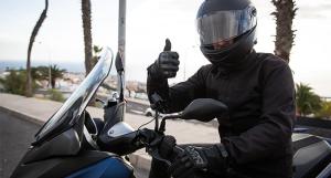 Un homme casqué assis sur son scooter le pouce en l'air