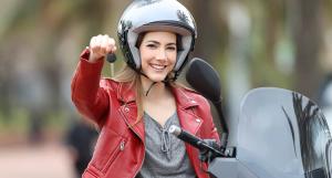 Une jeune femme casquée sur un scooter brandissant une clé