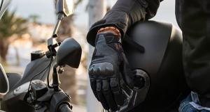 Gros plan sur la main gantée d'un scootériste tenant son casque