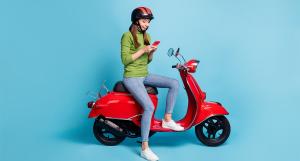 Une jeune femme avec un pull vert assise sur un scooter rouge
