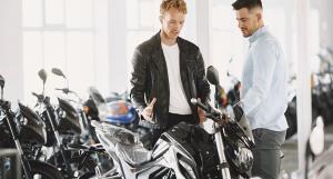 Un homme en blouson en cuir discutant avec un vendeur de motos