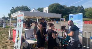 Un groupe de personnes devant le stand et le kakémono ASSU 2000