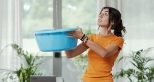 femme avec un seau d'eau suite à une fuite dans son appartement