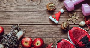 Des haltères roses, une paire de baskets rouges, une corde à sauter, des pommes posés à côté de décorations de Noël