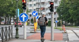 Un homme casqué sur une trottinette électrique